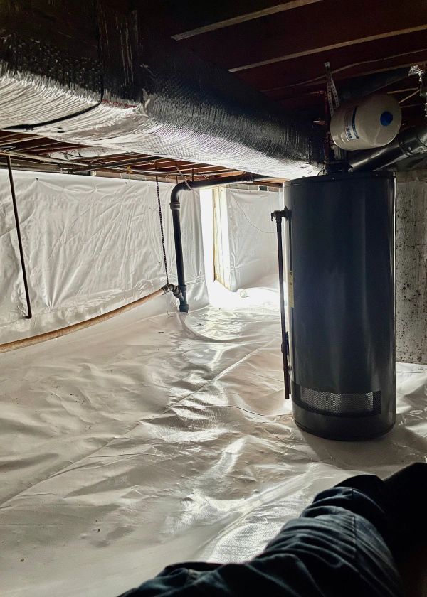 A person is laying in a basement with a water heater.