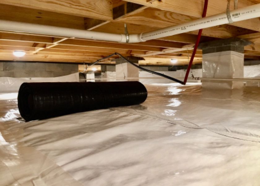 A roll of plastic is sitting on the floor of a basement.