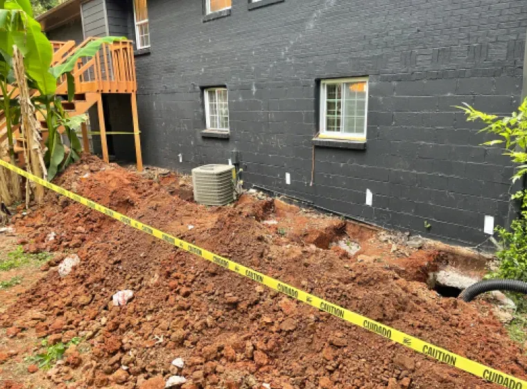 A large pile of dirt is in front of a black house.