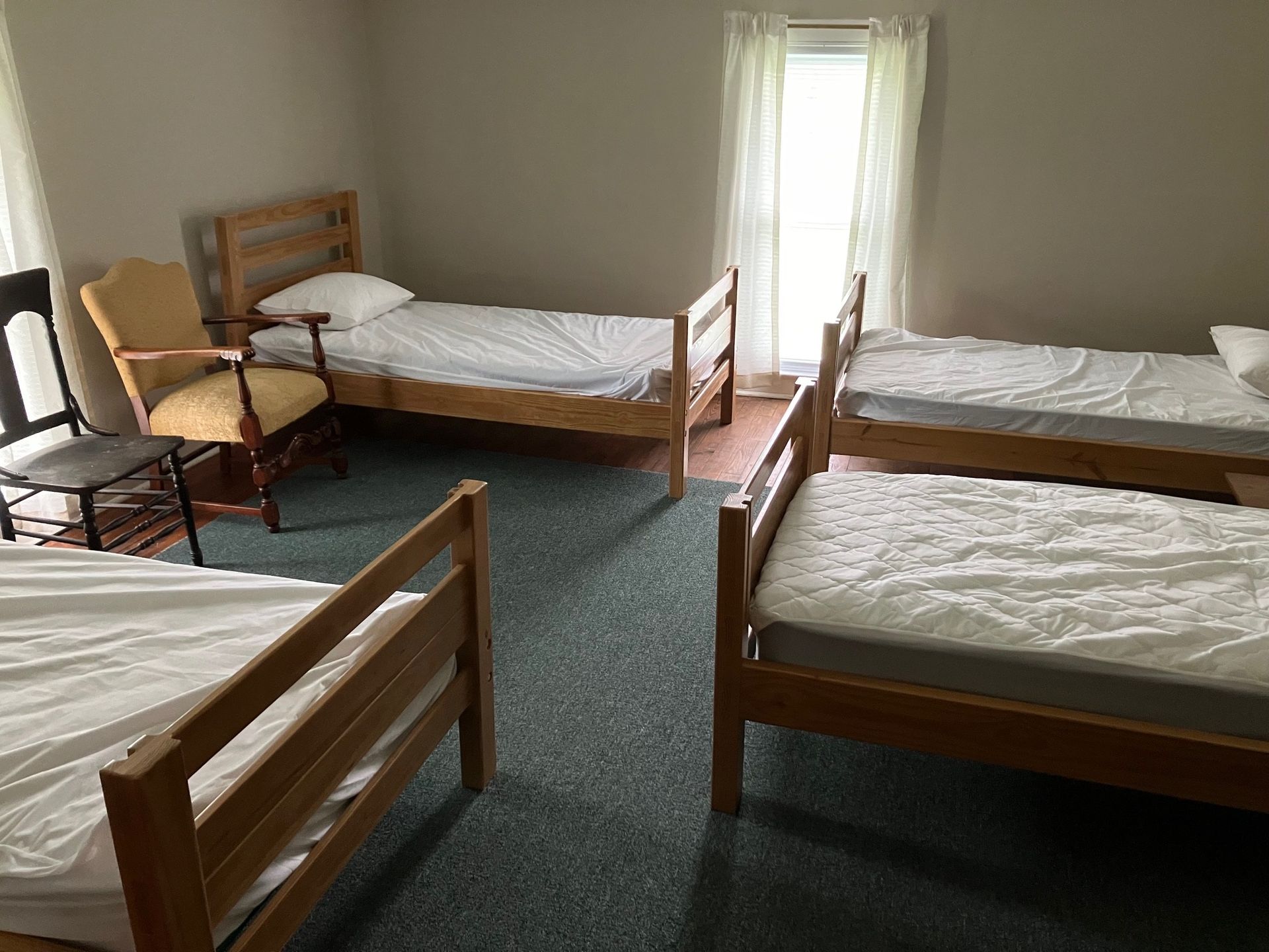 A room with four beds and a rocking chair