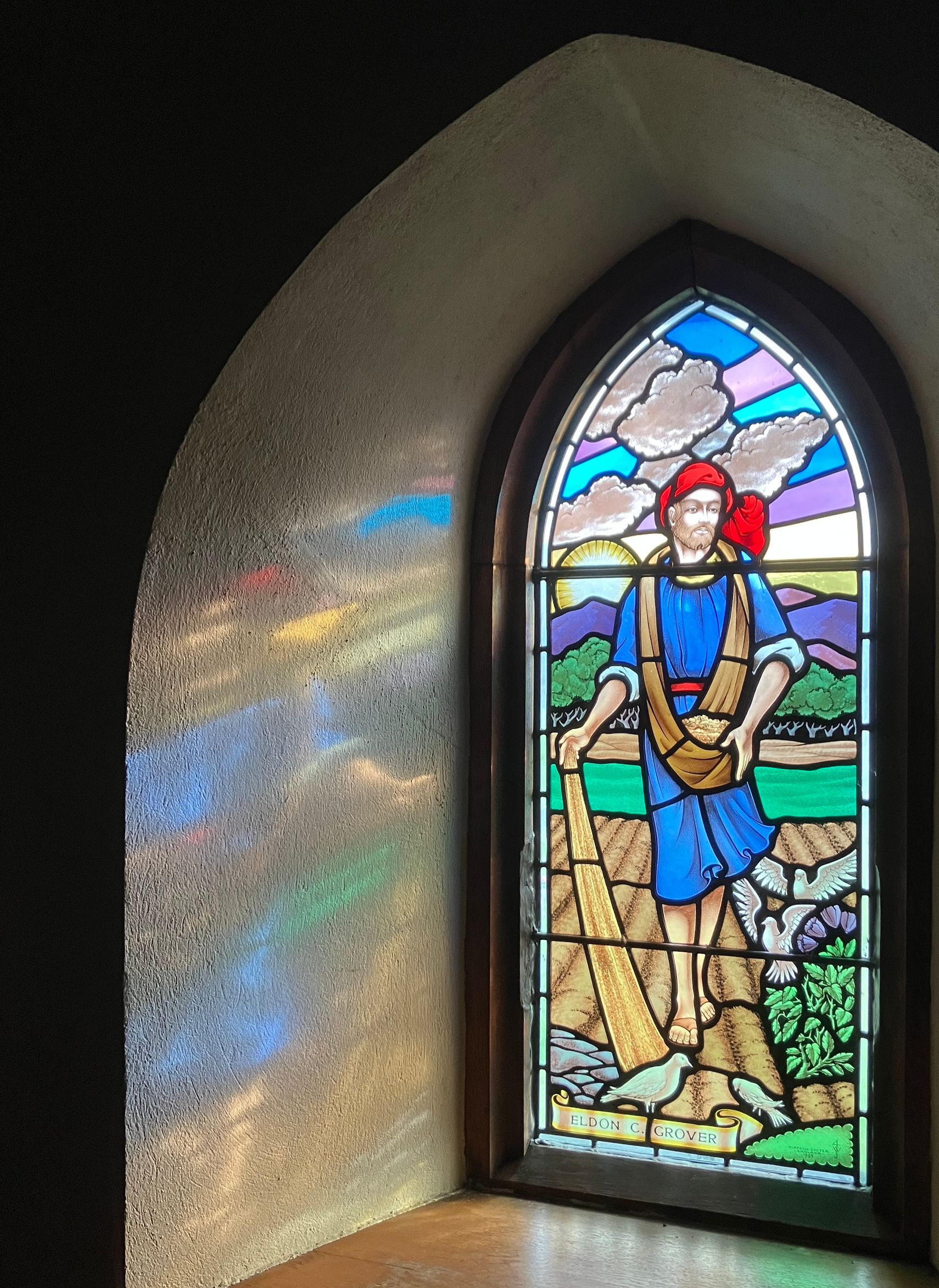 A stained glass window shows a man standing on a rock