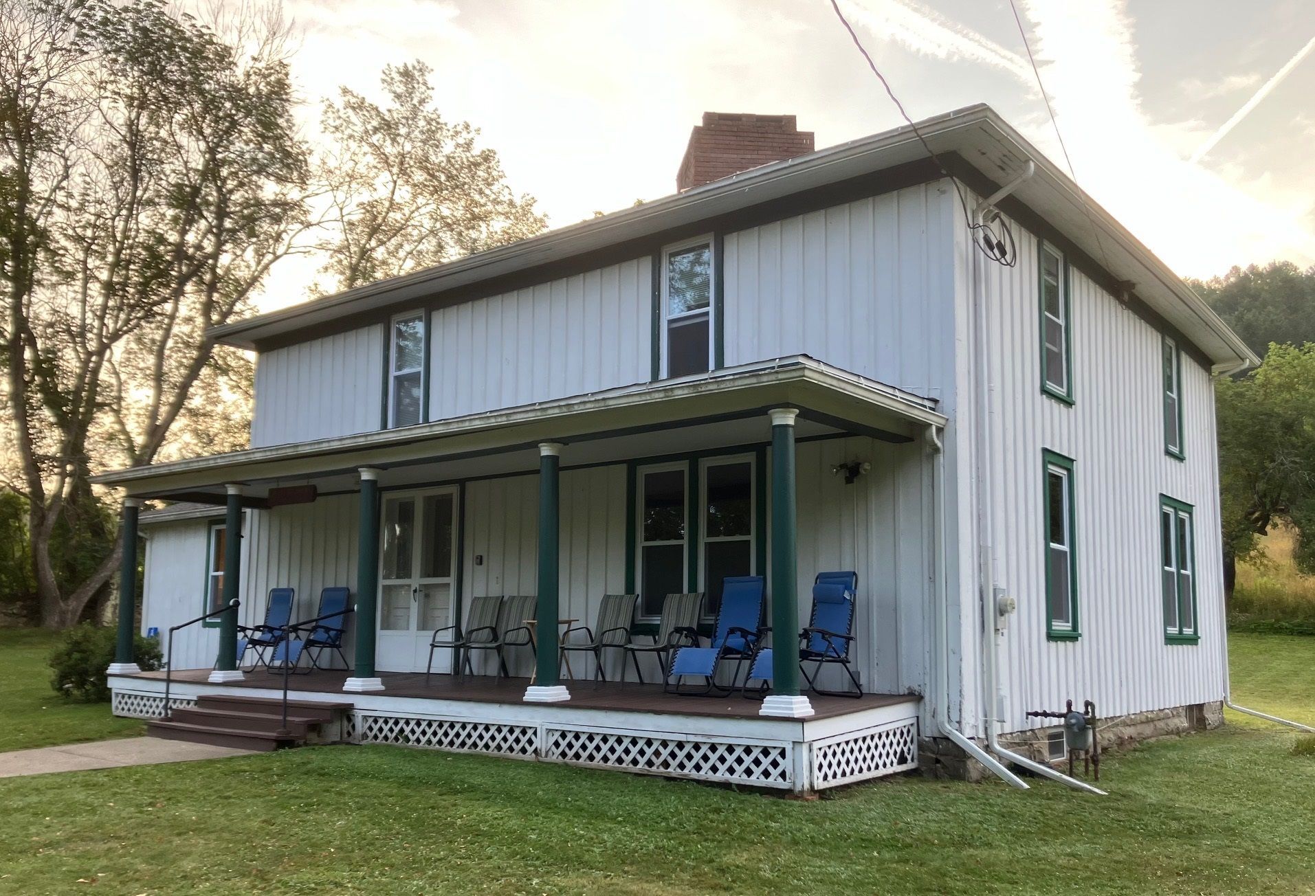 A white house with a porch and chairs on it
