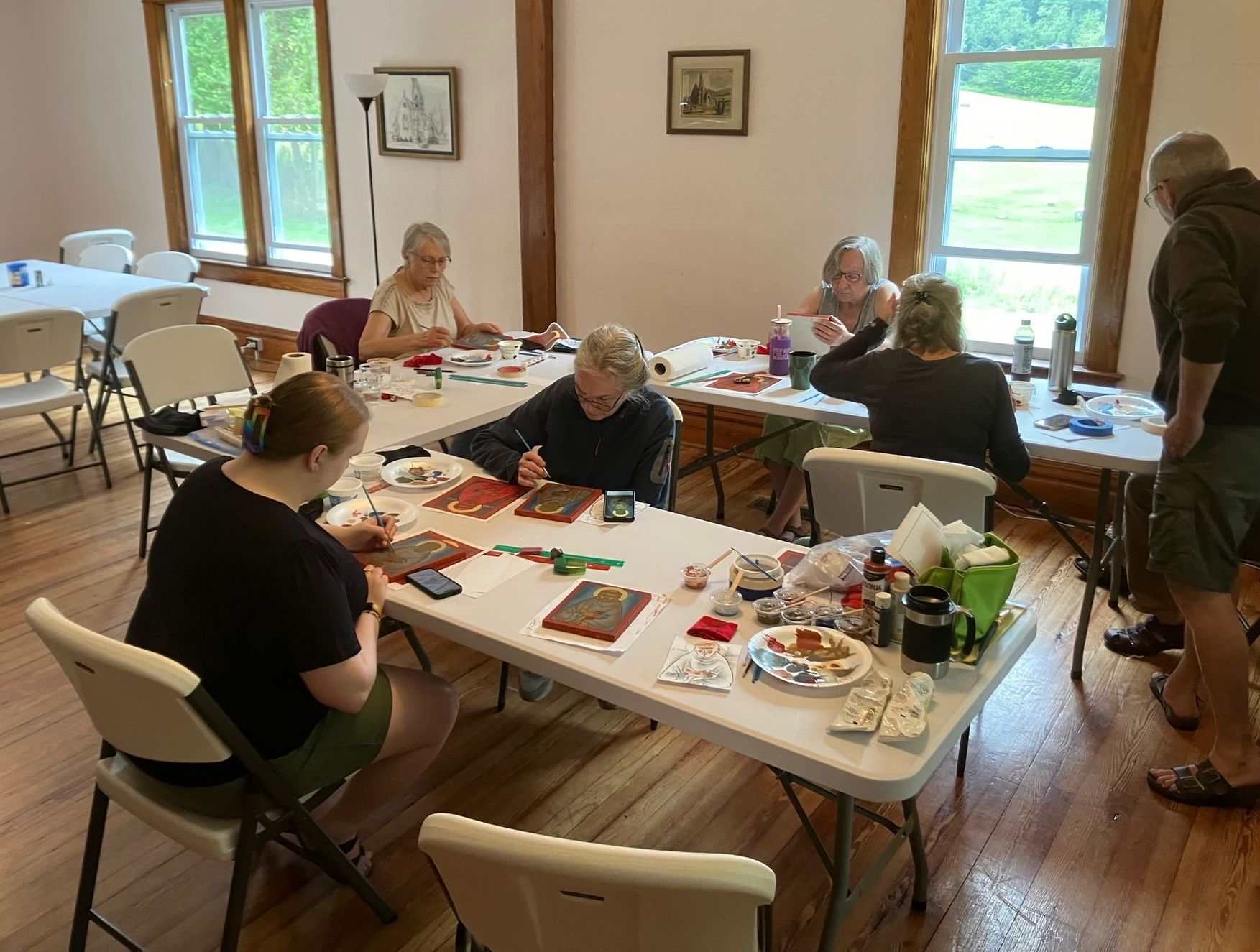 A group of people are sitting around a table painting