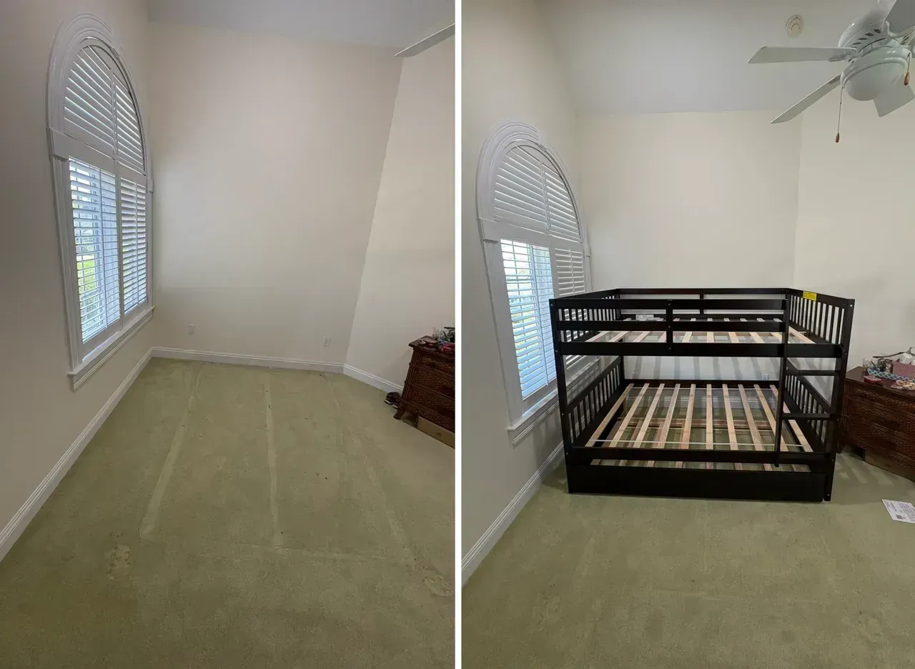 Small bedroom with beige walls, carpet, window, and a black crib on the right.