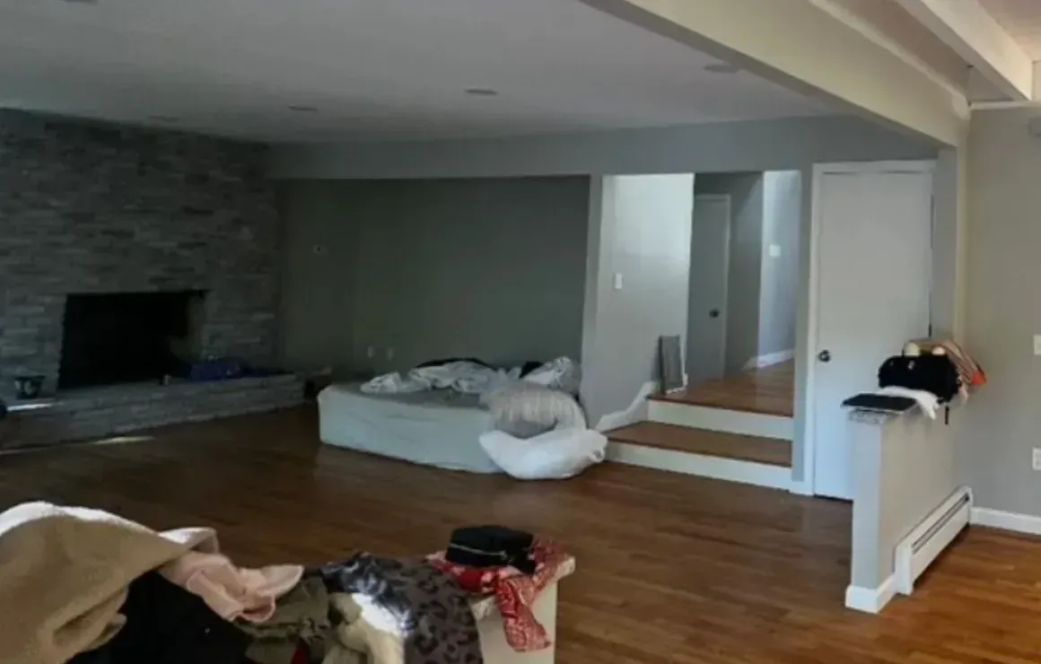 Living room with hardwood floors, fireplace, low bed, and stairs leading to a hallway