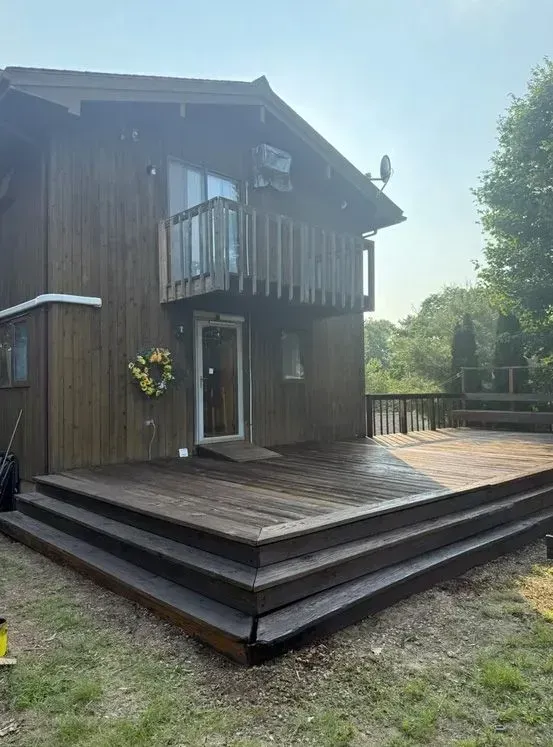 Wooden house with a raised deck and balcony in a sunny yard