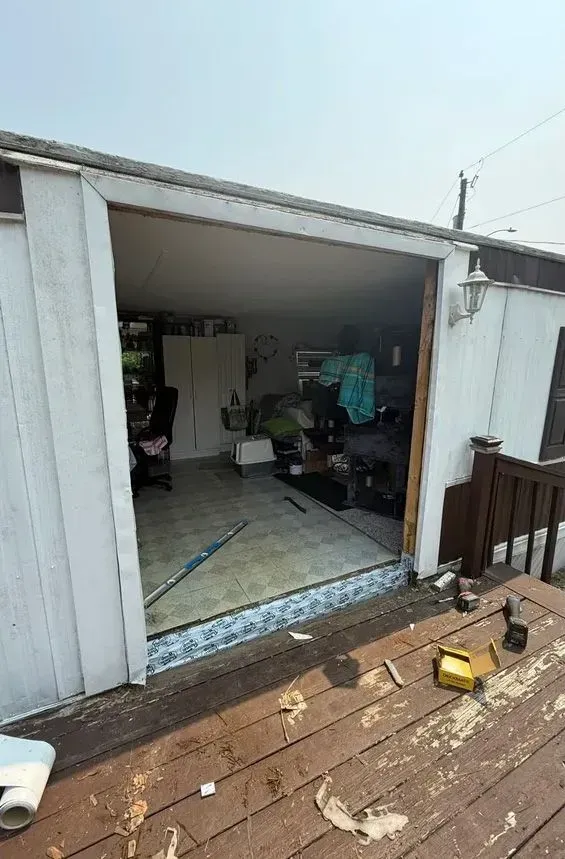 Open shed with cluttered interior and damaged wooden deck in foreground