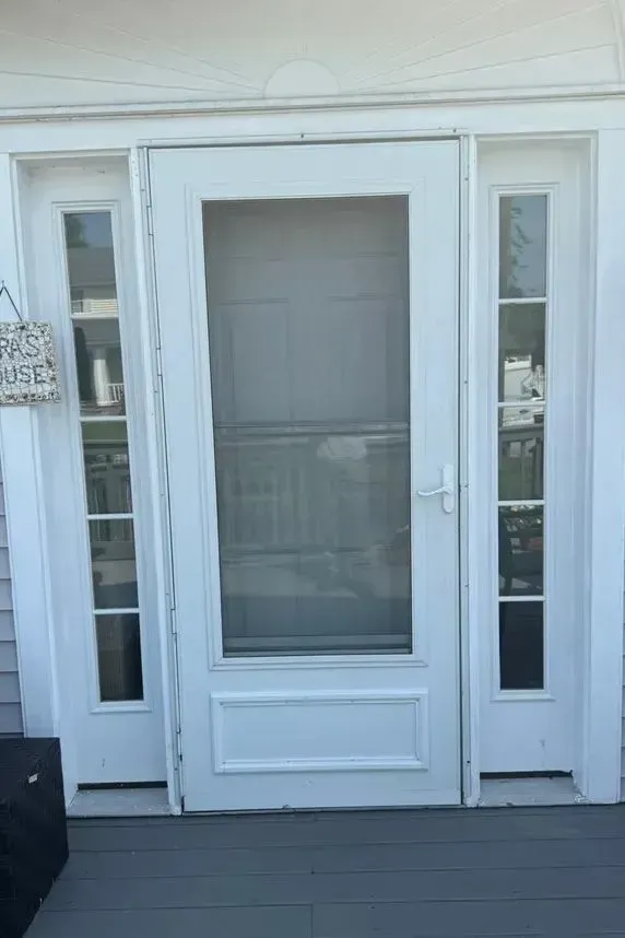White front door with glass panel and narrow sidelights on a porch with gray flooring