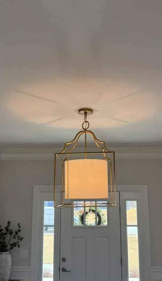 Brass lantern pendant light glowing above a white front door with sidelights.