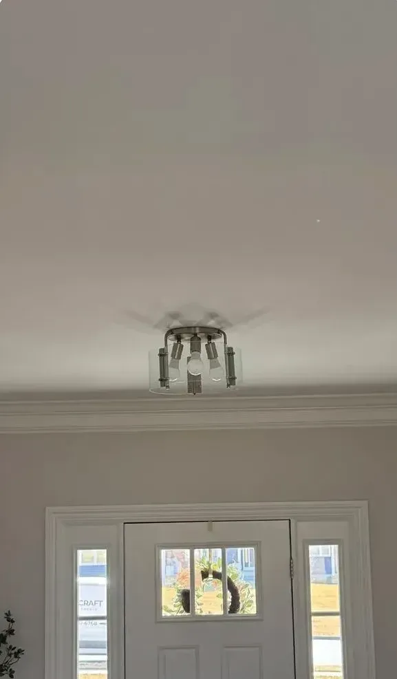 White ceiling with a small flush-mount light above a front door and window frame.