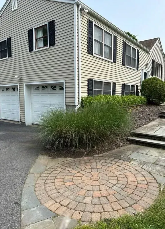Suburban townhouse exterior with garage, stone walkway, and ornamental grass in front yard