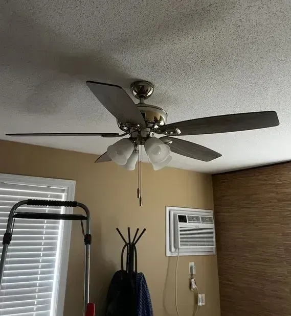 Ceiling fan with light fixture in a room with an air conditioner and exercise equipment