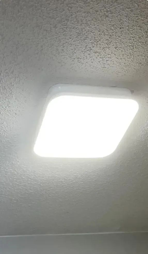 Bright ceiling light fixture on a textured white ceiling.