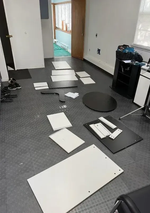 Scattered white and black floor panels in a room, with tools and equipment near an open doorway.