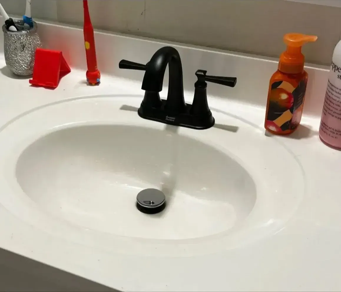 Bathroom sink with black faucet, white counter, and soap dispensers on either side.