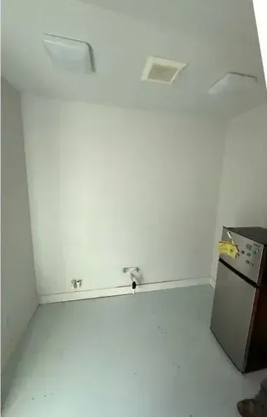 Empty laundry room with white walls, utility hookups, ceiling vents, and a stainless-steel appliance on the right.