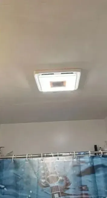 Ceiling vent light above a blue shower curtain in a bathroom