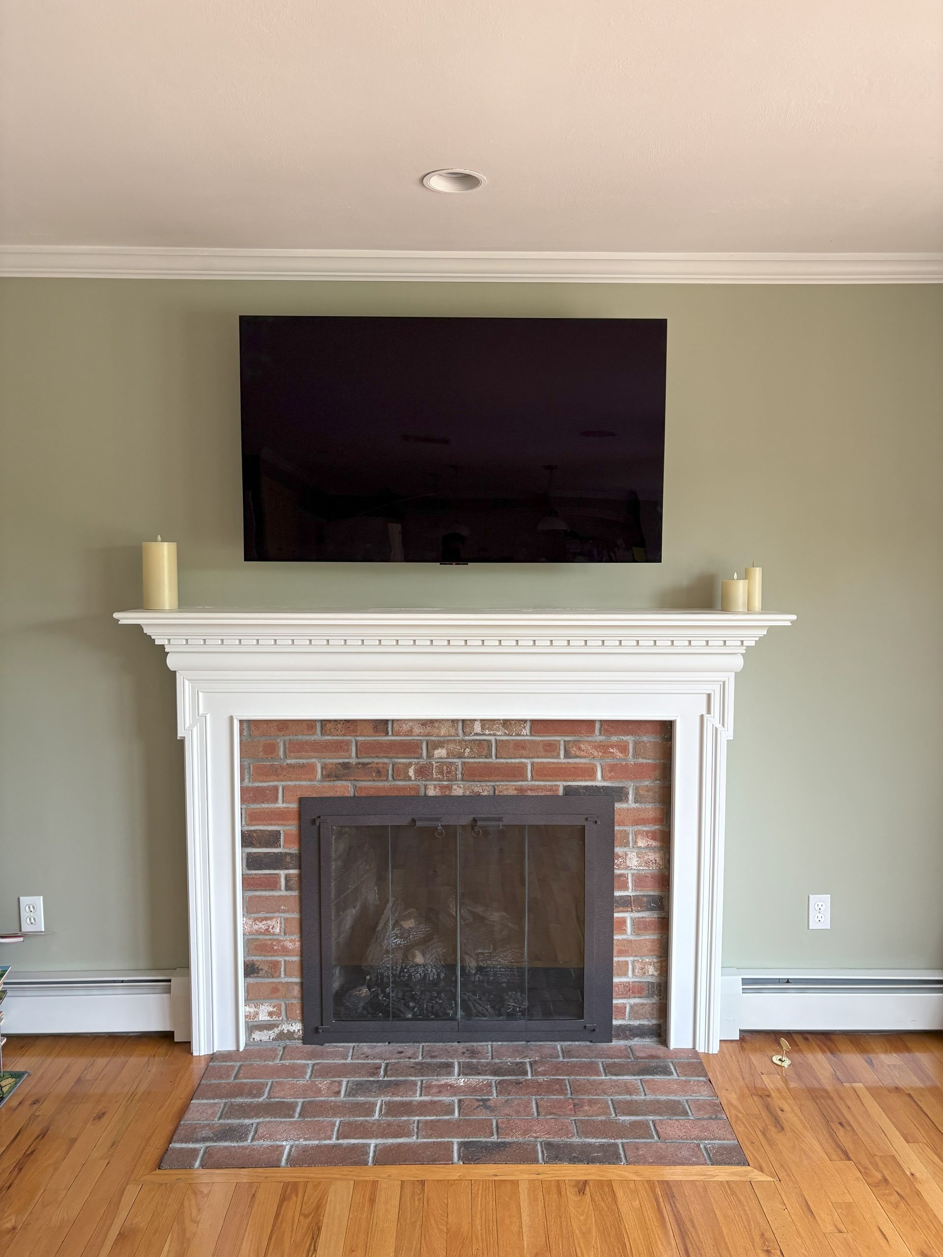 Living room fireplace with white mantel and wall-mounted TV above brick surround
