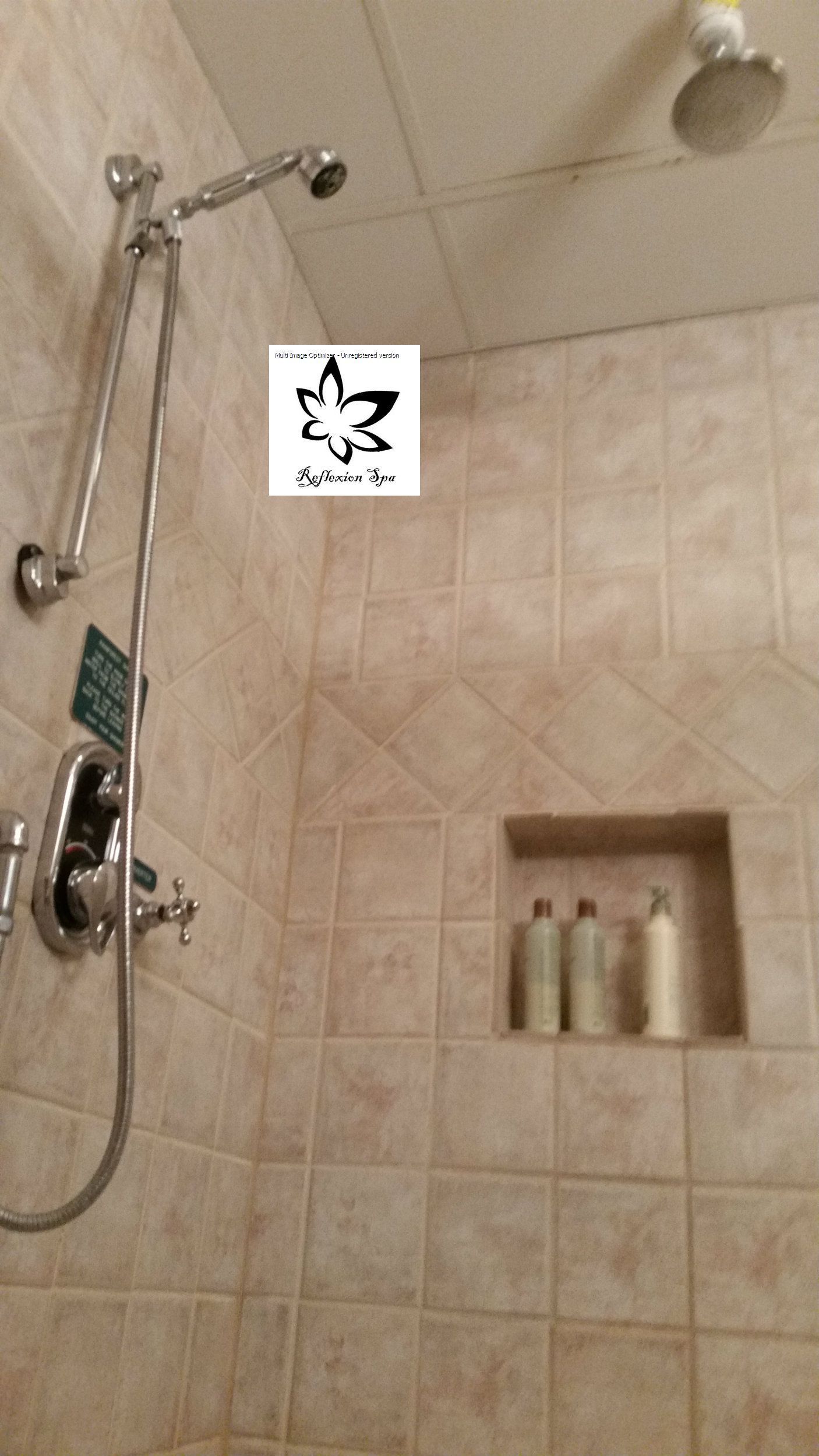 A bathroom with a shower head and a soap shelf