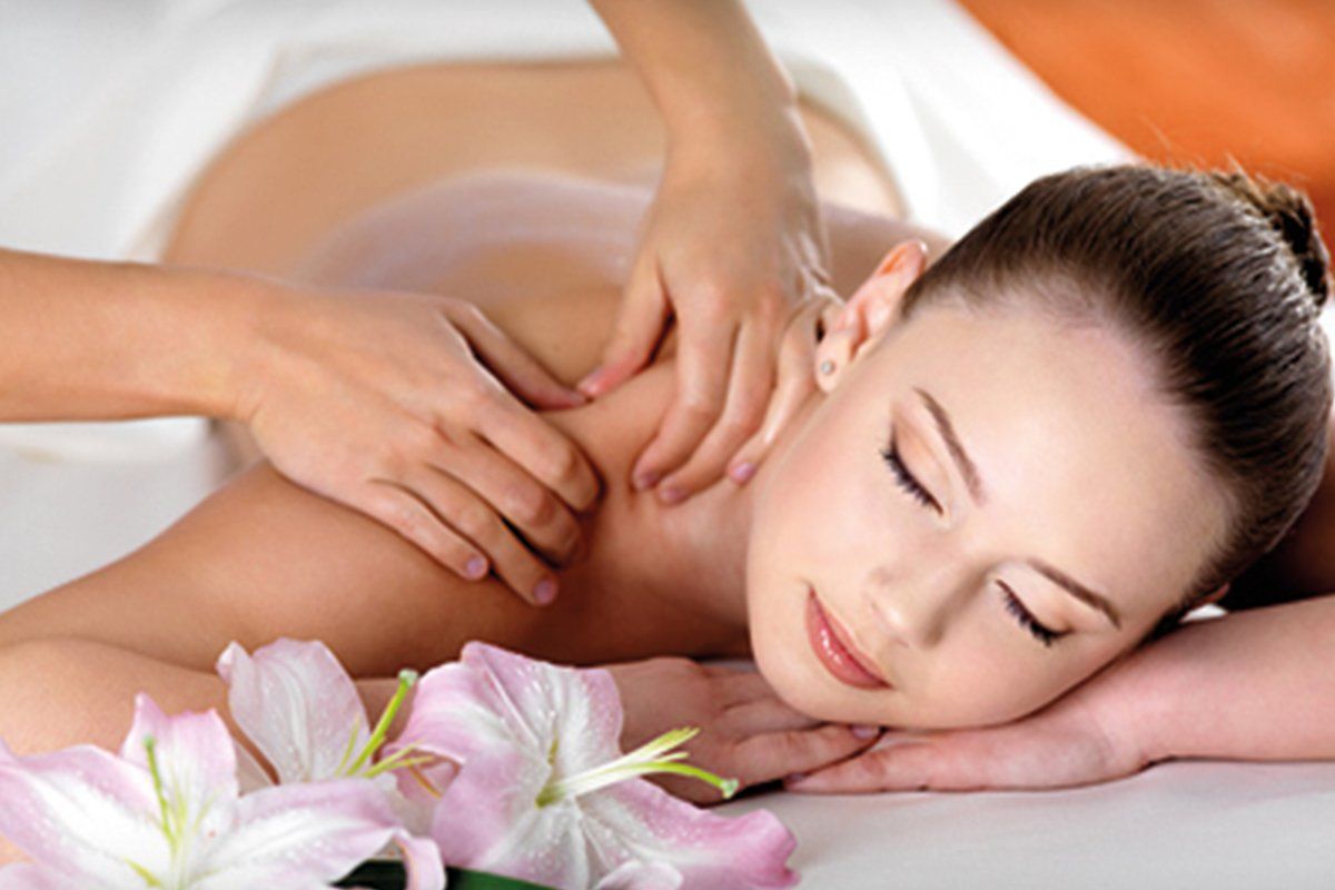 A woman is laying on a bed getting a massage.