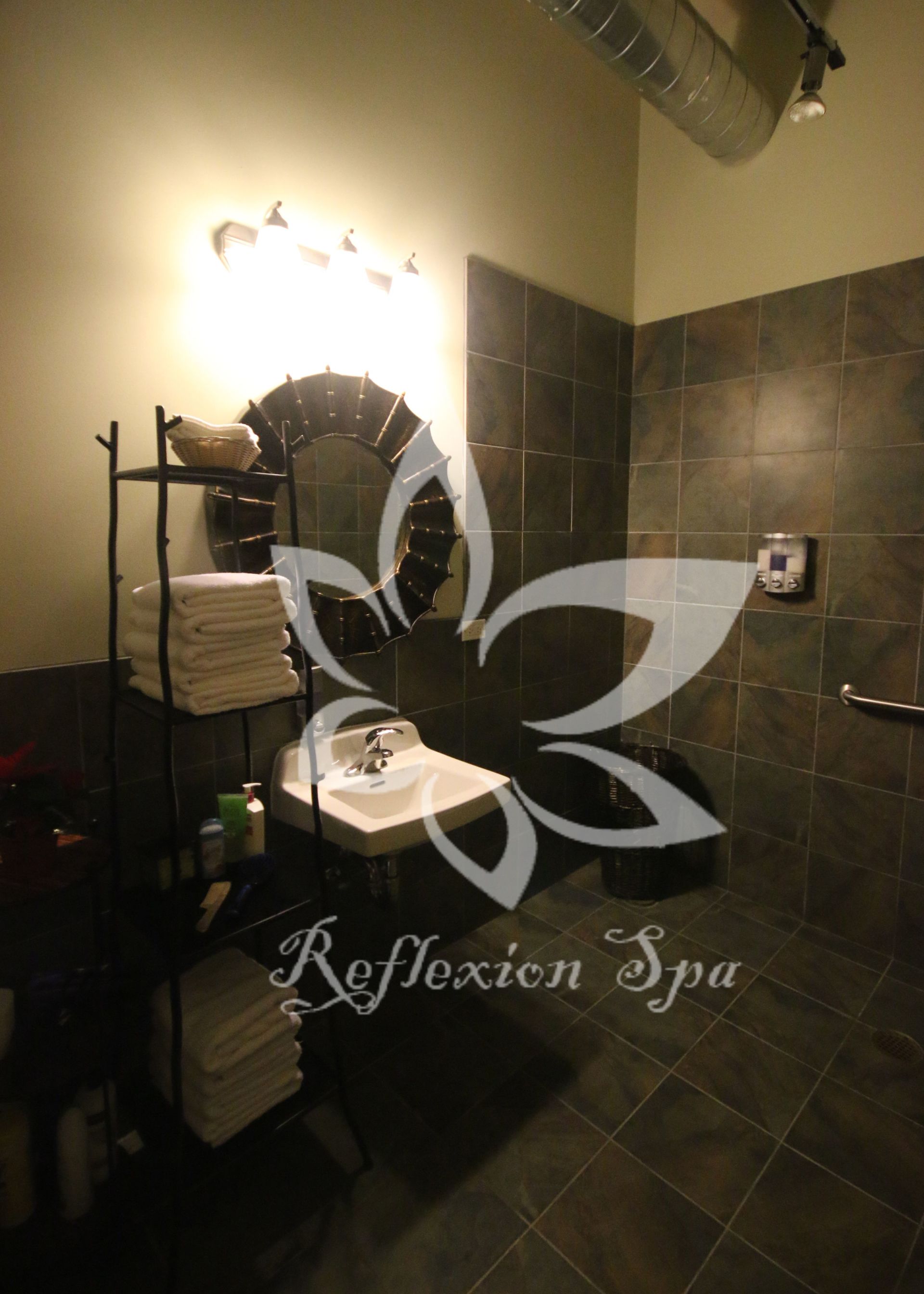 A bathroom with a reflection spa logo on the wall