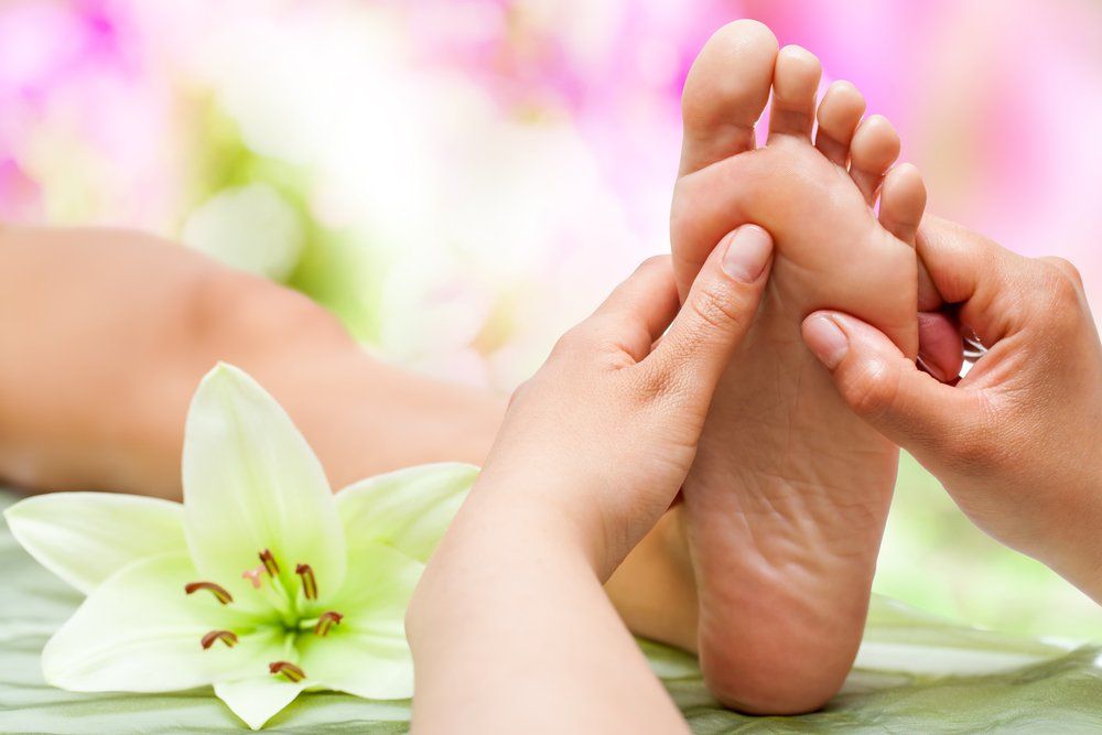 A person is getting a foot massage with a flower in the background.