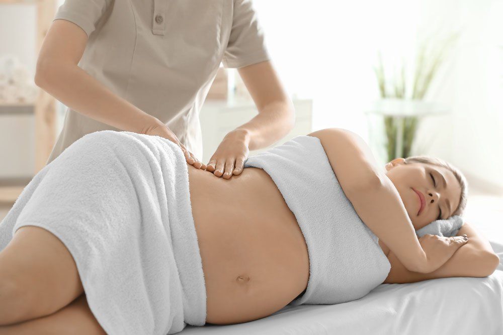 A pregnant woman is getting a massage at a spa.