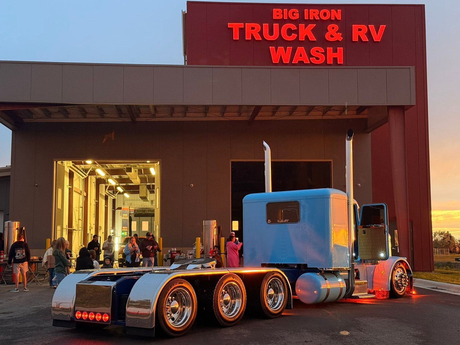 Blue semi-truck parked outside Big Iron Truck & RV Wash at dusk