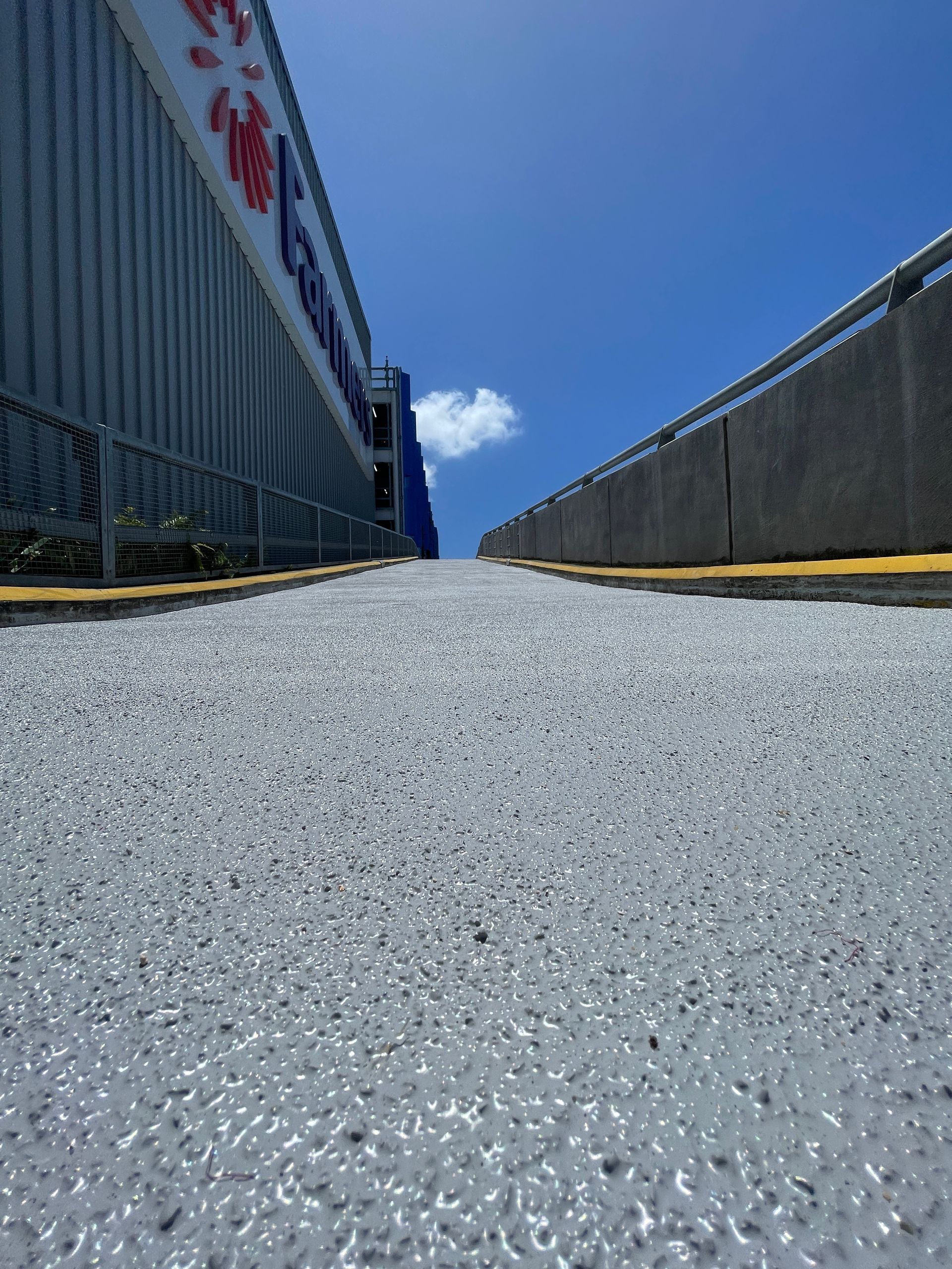 Car park ramp with grey surface, advertisement for fast curing system. Workers in high-vis vests.