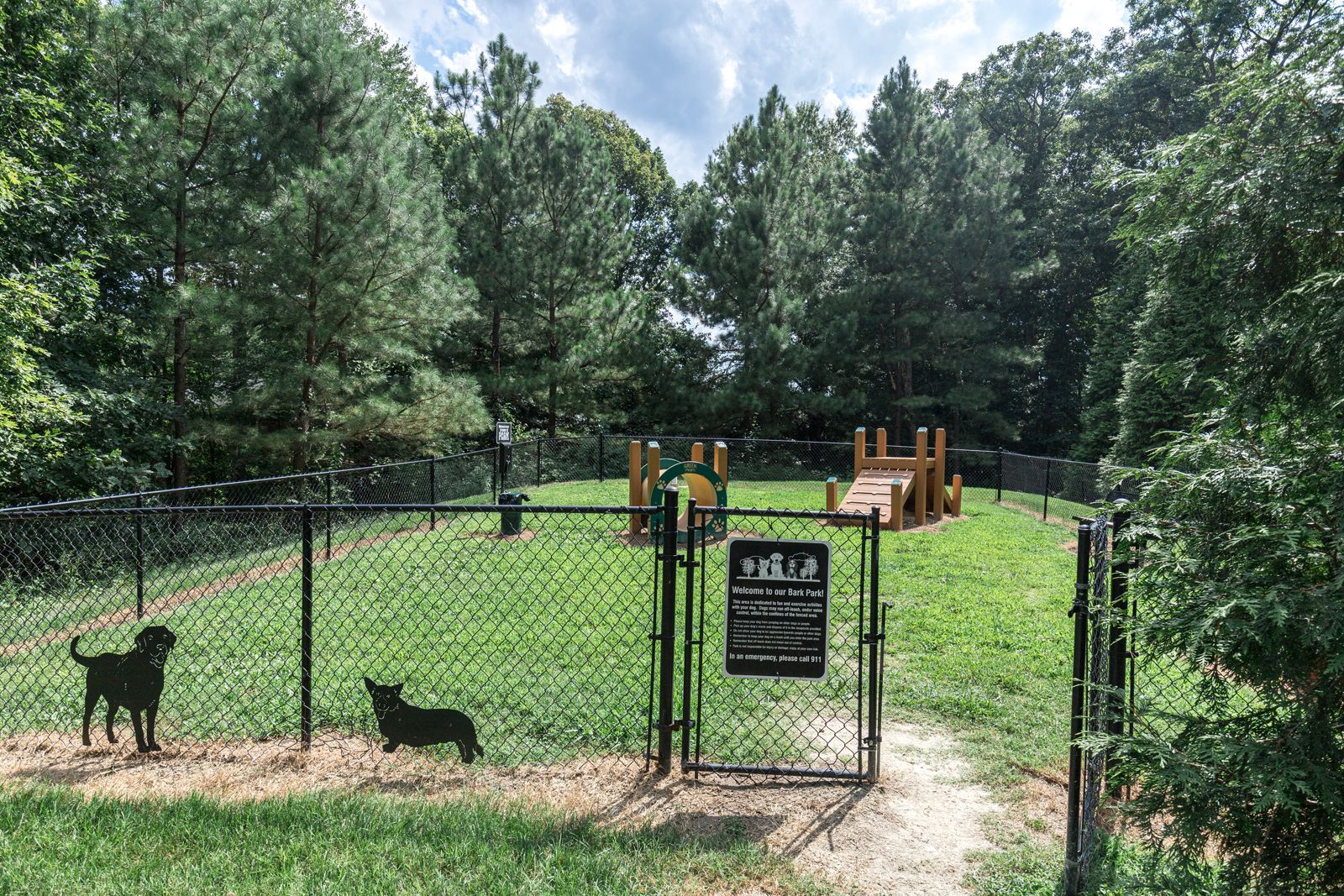 A dog park with a chain link fence and a playground.