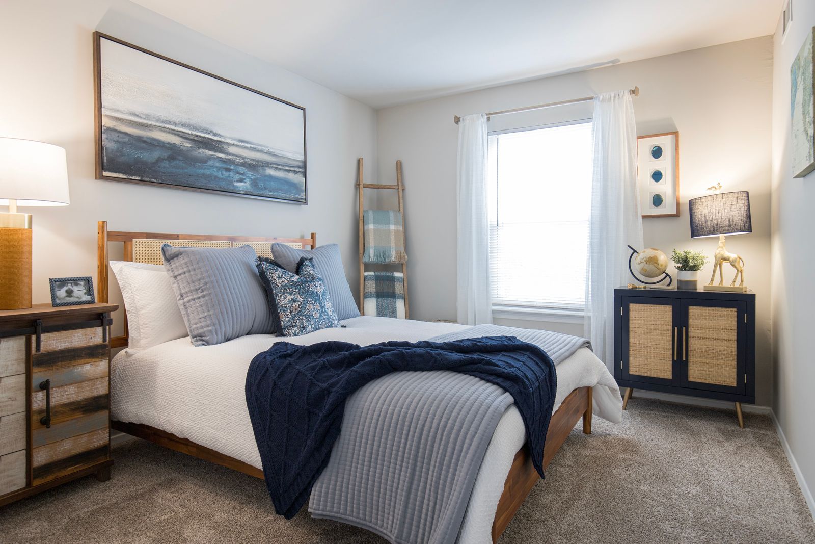 A bedroom with a bed , nightstand , dresser and window.