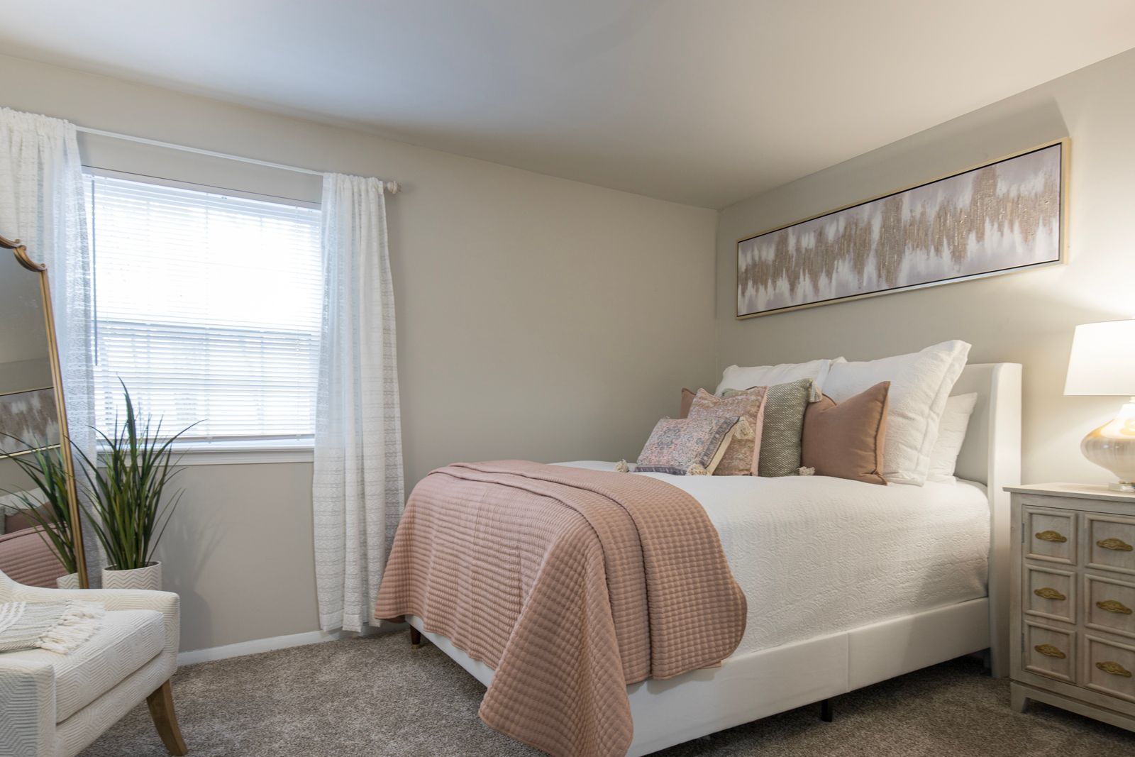 A bedroom with a bed, nightstand, chair, and window.