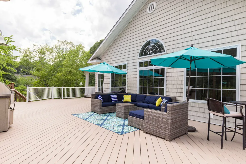 A large deck with a couch , chairs , umbrellas and a table.