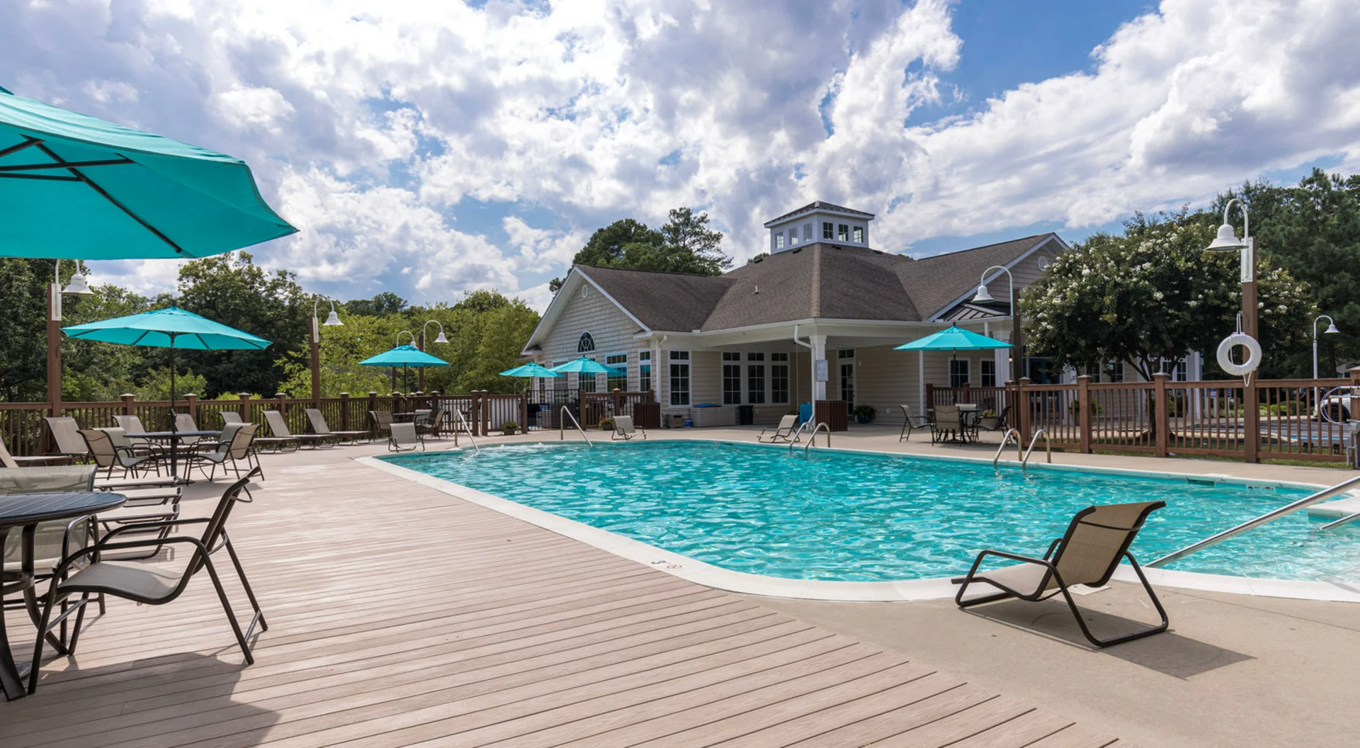 There is a large swimming pool with umbrellas and chairs around it.