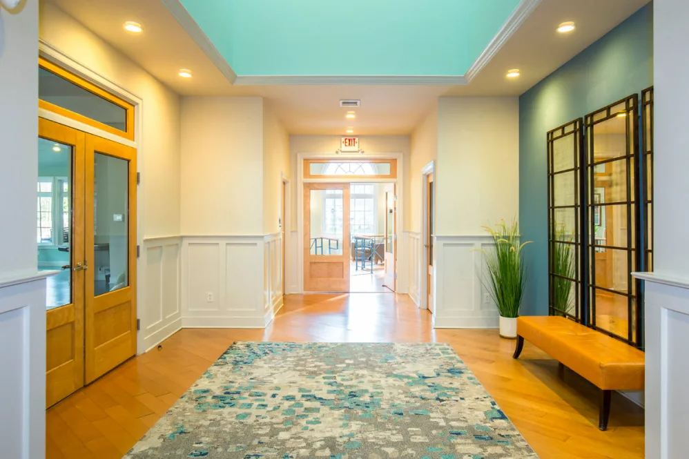 A hallway in a house with a rug and a bench.