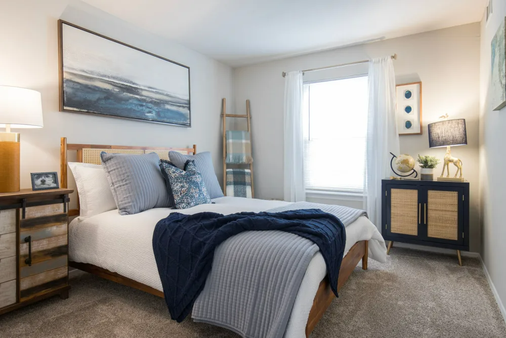 Modern bedroom with bed, wall art, dresser and oversized window.