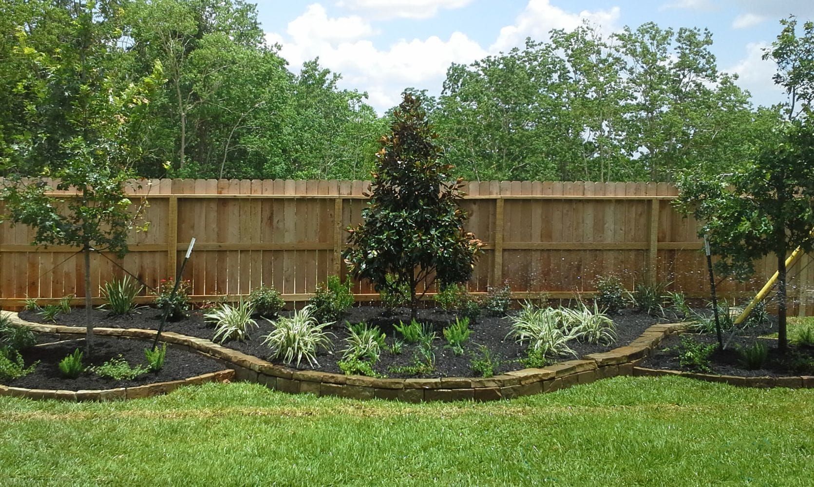 Custom landscaping design with curved flower beds, plants, and irrigation system in Plant City, FL