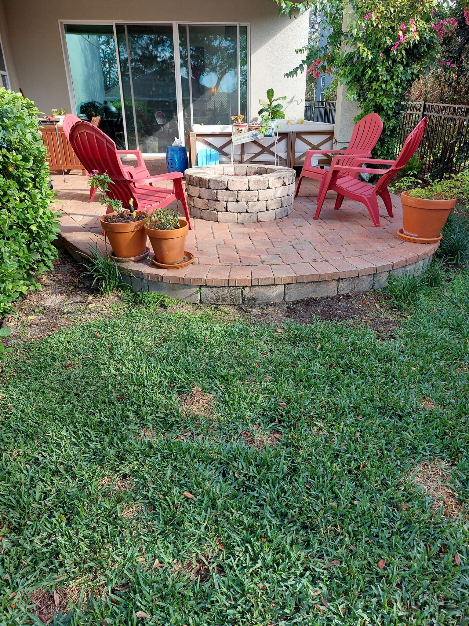 Outdoor patio landscaping design with brick pavers, seating area, and decorative plants in Plant City, FL