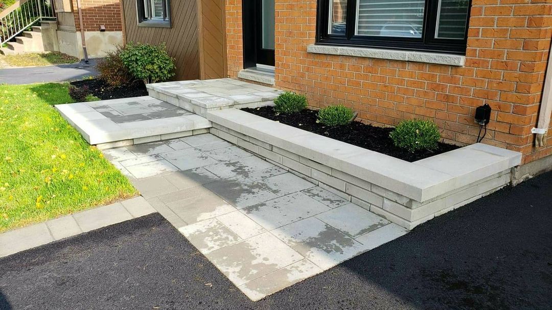 Une maison en briques avec une allée en béton menant à la porte d'entrée.