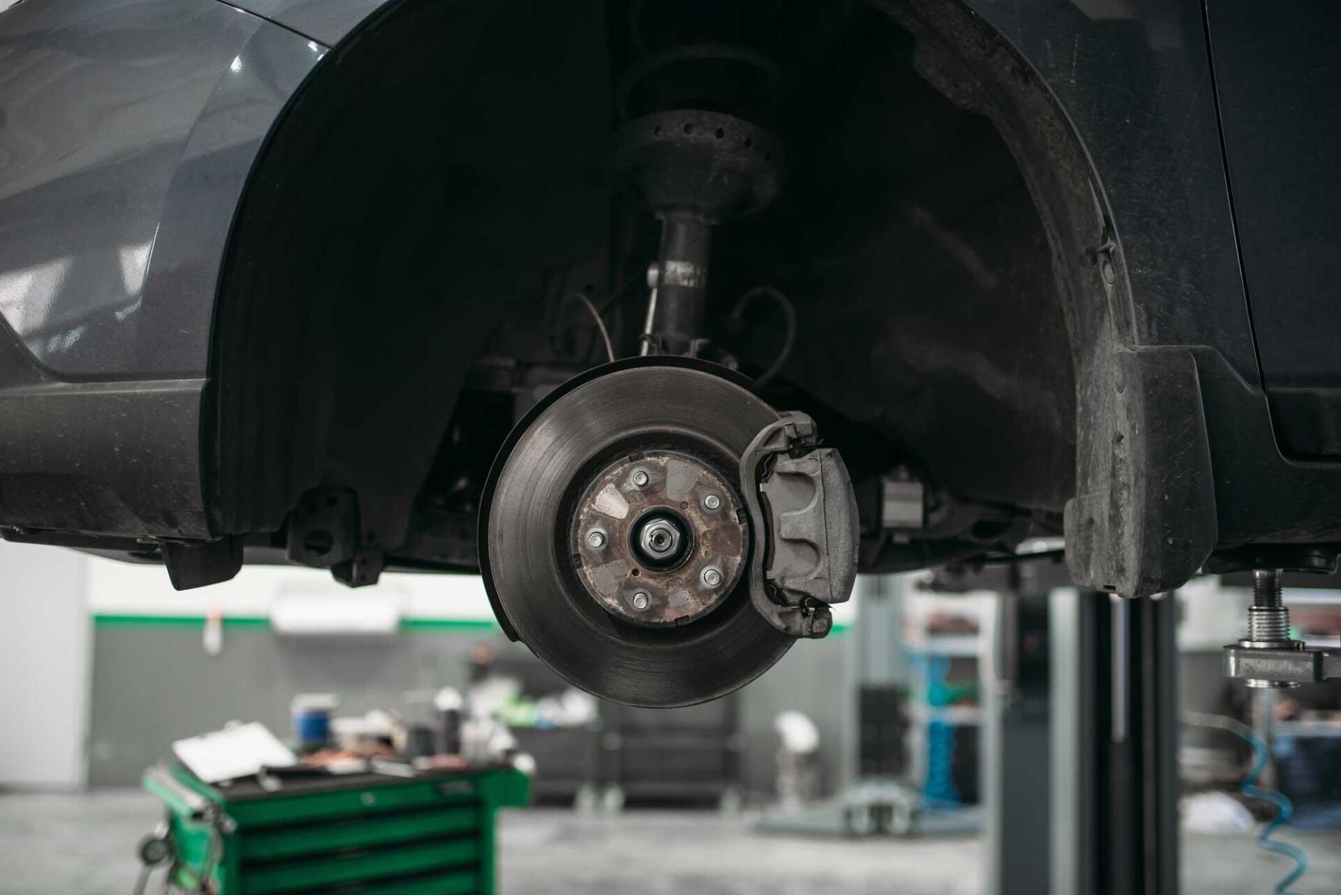 A car is being repaired on a lift in a garage.