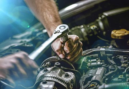 A man is working on a car engine with a wrench.