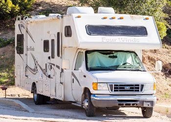 A white rv is parked on the side of the road.