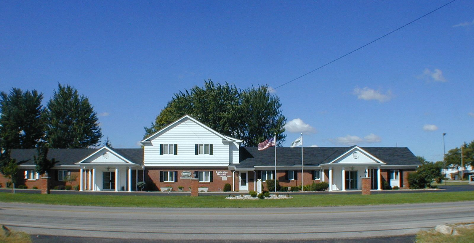 The front door of a house with a porch and plants in front of it.