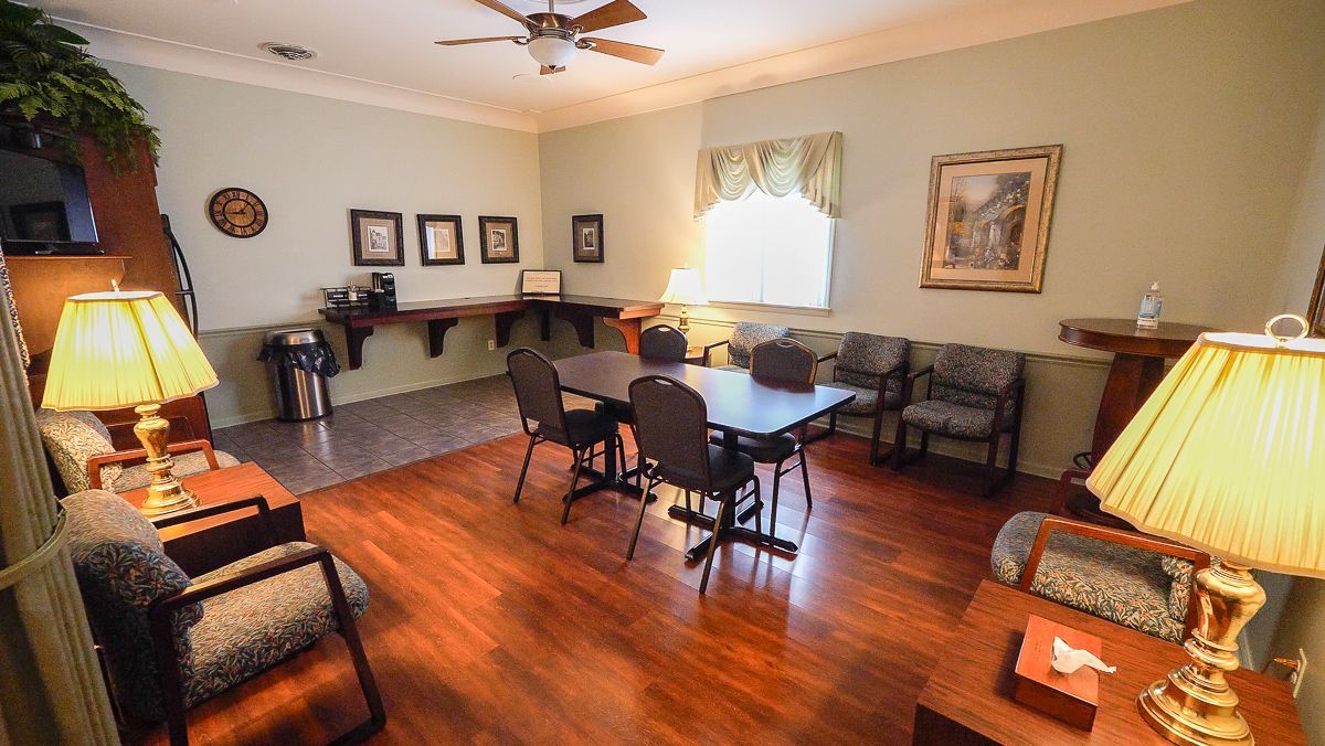 Waiting room with seating, table, lamps, and artwork; hardwood floors.