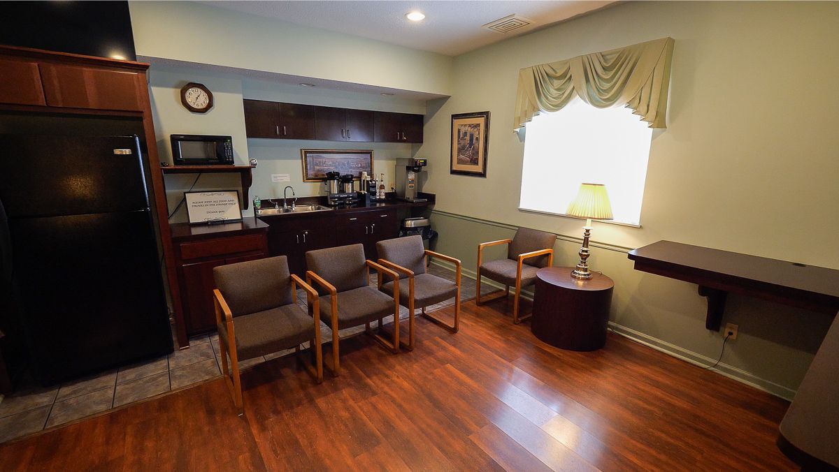 Waiting room with brown chairs, hardwood floor, window, and kitchenette.