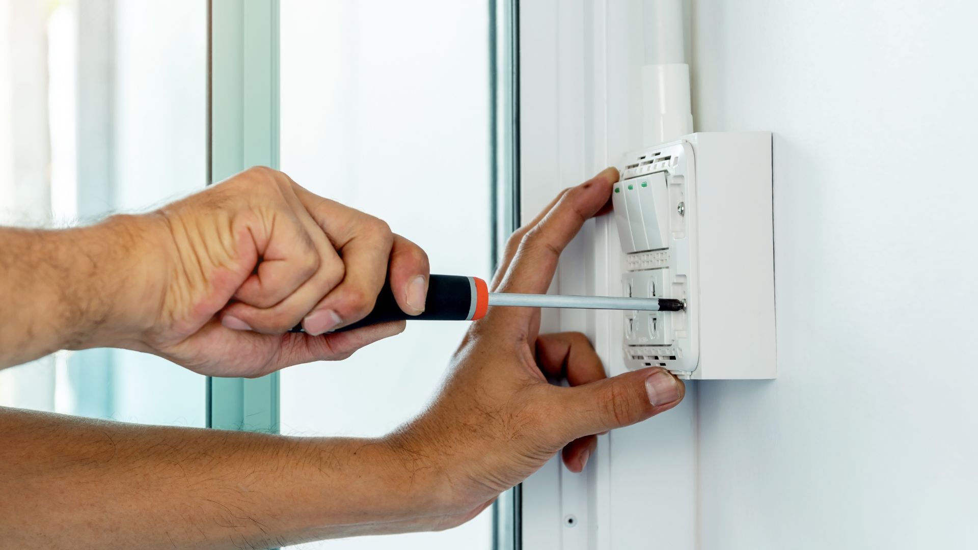 A man is fixing a door with a screwdriver.