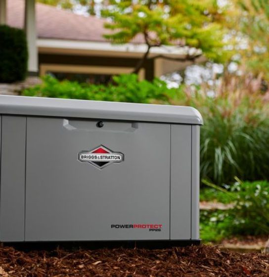 A gray generator is sitting in front of a house.