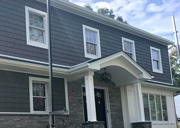 A large house with a porch and a lot of windows.