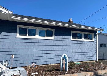 A blue house with white windows and a boat in front of it.