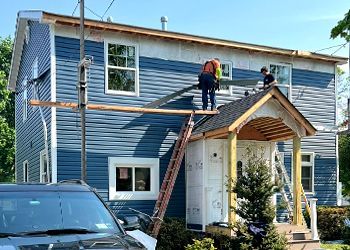 Two men are working on the roof of a house.